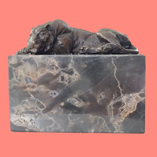 A bronze sculpture of a lying tiger mounted on a marble base.