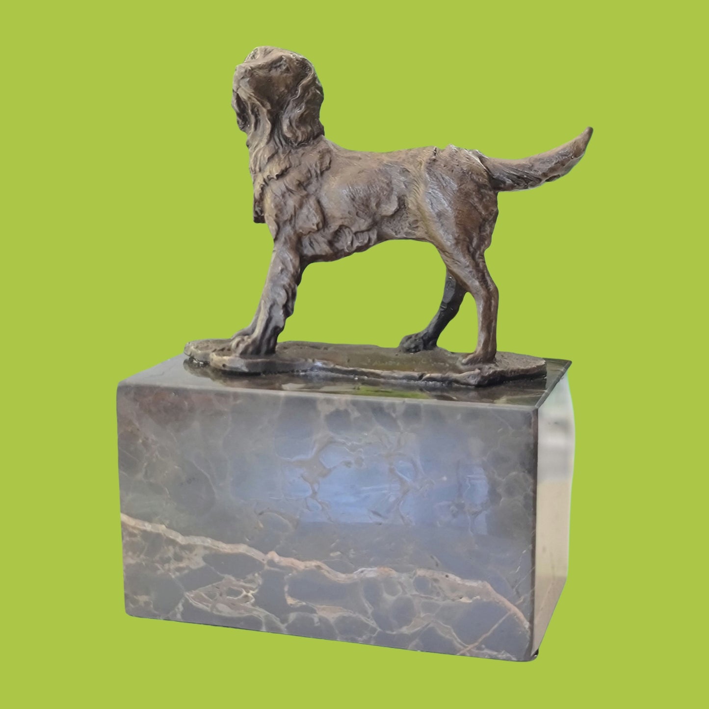 A solid bronze sculpture of a Spaniel dog mounted on a marble base.