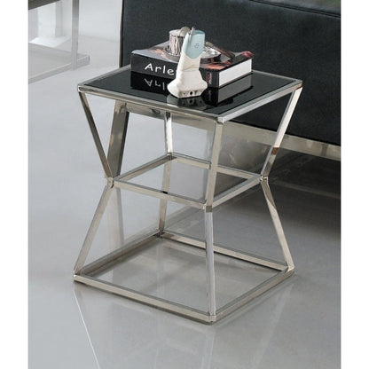 A polished stainless steel side table with black tempered glass top, with items placed on top in a showroom setting.