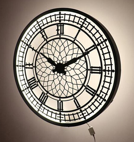 A 55 cm black and white wall clock with a geometric pattern, featuring a lamp mechanism, hanging on a wall.